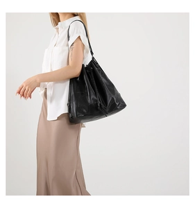 Detail of black quilted leather bucket bag with drawstring closure and slim shoulder strap