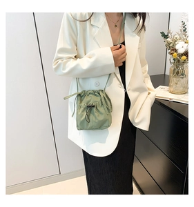Detail of light green nylon bucket bag with drawstring closure and slim shoulder strap