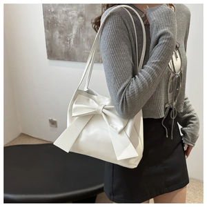 Close-up of white rectangular shoulder bag featuring a large decorative bow detail