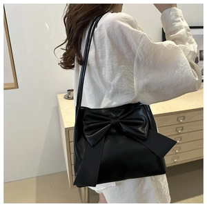 Détail d'un sac cabas noir en similicuir avec un grand nœud décoratif et une bandoulière