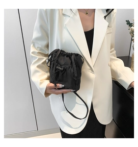 Detail view of a black drawstring bucket bag worn over a stylish white blazer for women
