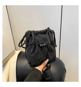 Detail of black nylon drawstring bucket bag showing adjustable cords and smooth texture