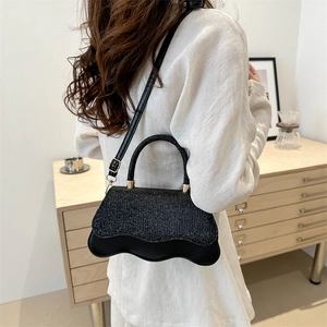Sac à main noir pailleté élégant avec bord ondulé et détails dorés sur un mannequin