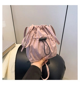 Detail of pink nylon bucket bag featuring drawstring closure and front pocket for casual use
