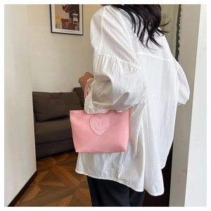 Detail of pink bucket bag with heart smile patch held by model in casual interior