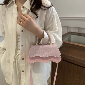 Mini sac à main rose à paillettes avec base ondulée sur un mannequin en chemise blanche