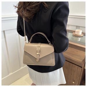 Rear view of khaki leather tote with gold buckle and top handle worn by a model