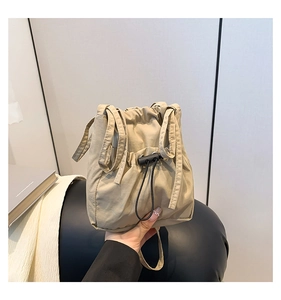 Detailed close-up of khaki canvas bucket bag with adjustable black drawstring and strap