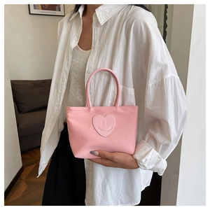 Close-up of pink heart smiley emblem on a smooth nylon mini tote bag with handles