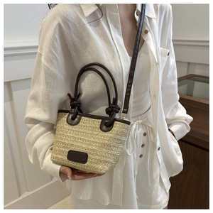 Close-up of beige woven beach tote bag featuring dark brown leather straps and handles