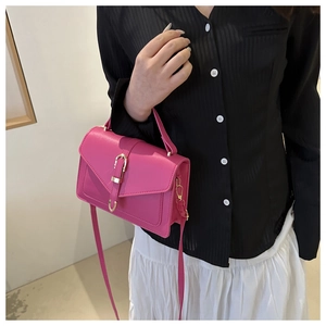 Detailed close-up of rose pink crossbody bag with gold metal buckle and leather texture