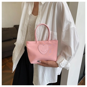 Close-up of pink mini bucket bag featuring a cute heart patch with a smiling face