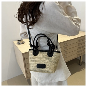 Detail of woven straw tote bag with black trim and elegant knotted handle design