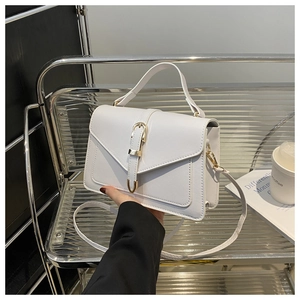 Detail of white PU leather crossbody bag with elegant gold buckle and envelope flap