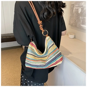 Detail of colorful striped woven hobo bag with brown leather strap and metal ring