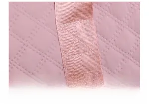 Detailed macro shot of pink quilted fabric and reinforced cross-stitching on travel bag
