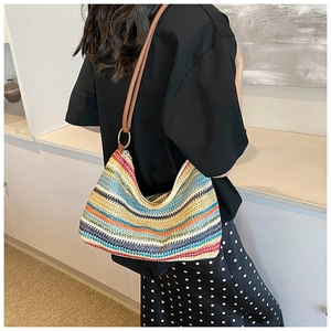 Detail of colorful striped woven shoulder bag featuring a brown leather strap and gold ring