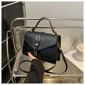 Detail view of black matte leather small square bag with golden buckle and top handle