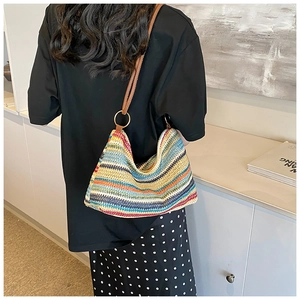 Detail of colorful woven crochet shoulder bag with brown leather strap and gold metal rings