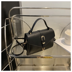Detail of black crossbody bag featuring a golden U-shaped clasp and matte leather texture
