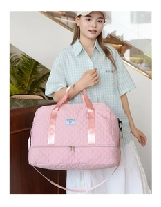 Close-up of pink quilted sports bag featuring a bottom compartment and a blue logo patch
