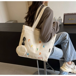 Detail of beige canvas tote bag with colorful embroidery and matching round coin purse pouch