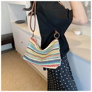 Detailed texture of colorful woven straw bag with brown leather strap and gold ring buckle
