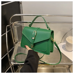 Detail of green faux leather crossbody bag with elegant gold buckle and precise stitching