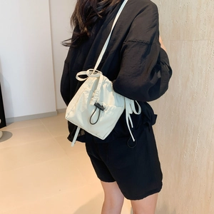 Minimalist cream drawstring bucket bag in lightweight nylon fabric for casual summer wear