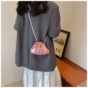 Pink metallic pleated cloud bag with elegant crossbody strap shown on a gray suit model