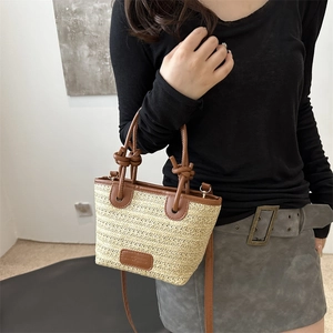 Women's woven straw beach tote bag with brown leather accents and adjustable shoulder strap
