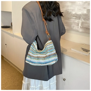 Detail of bohemian wavy woven straw bag with leather strap and colorful textured patterns