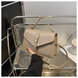 Detail of beige faux leather handbag with golden horseshoe buckle and textured finish