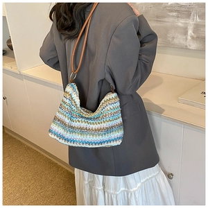 Close-up of bohemian woven hobo bag with colorful zigzag patterns and brown leather strap