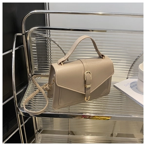 Detail of a chic khaki PU leather handbag on a stylish display shelf with coffee