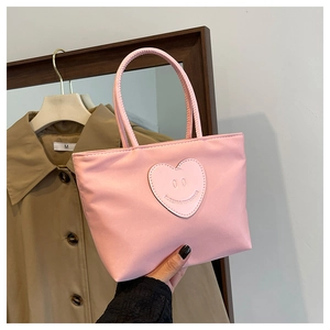 Detailed shot of pink nylon handbag with heart smiley patch and lightweight dual handles