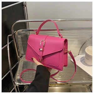 Detail view of pink structured handbag with gold horsebit buckle and slim shoulder strap