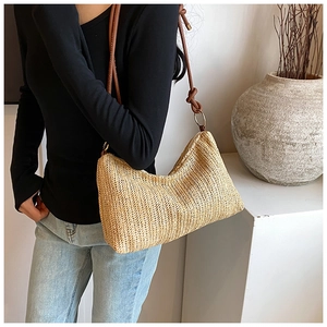 Close-up of woven straw shoulder bag with brown leather strap and elegant herringbone texture