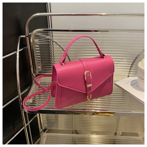 Close-up of hot pink crossbody bag featuring gold horseshoe buckle and matte texture
