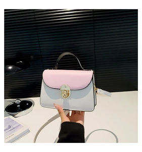 Close-up of pink and white crossbody bag with gold twist lock and black handle detail