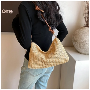 Detail of straw crescent shoulder bag with brown braided strap and gold metal hardware