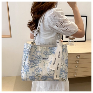 Detail of floral tote bag with chain strap and embroidered hydrangea patterns on the side