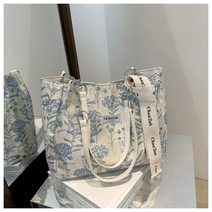 Detail of canvas tote bag with blue hydrangea print and metal chain leather strap