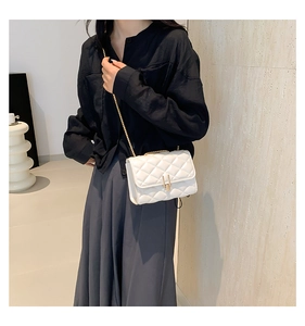 Detail shot of white quilted crossbody bag with gold metal chain and flip lock