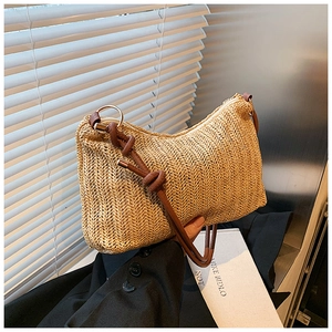 Close-up of woven straw texture with brown leather strap and gold metal ring detail