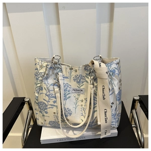 Detail of floral tote bag featuring a Fashion Instinct patch and decorative metal chain