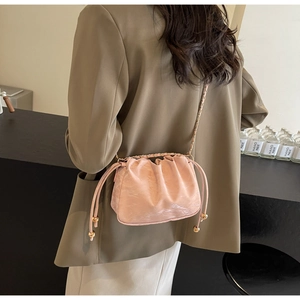 Detail view of pink drawstring bag with gold metal chain and shiny textured leather finish