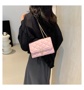 Close-up of pink quilted crossbody bag with gold chain strap worn by a model