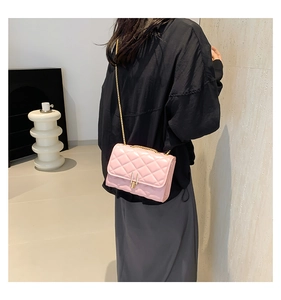 Close-up of pink quilted crossbody bag with gold chain strap on model's shoulder