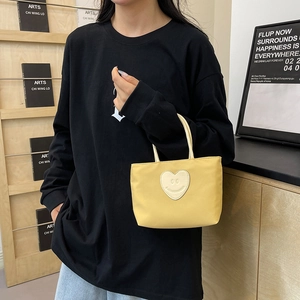 Yellow nylon bucket bag with heart smiley patch shown in a casual lifestyle setting